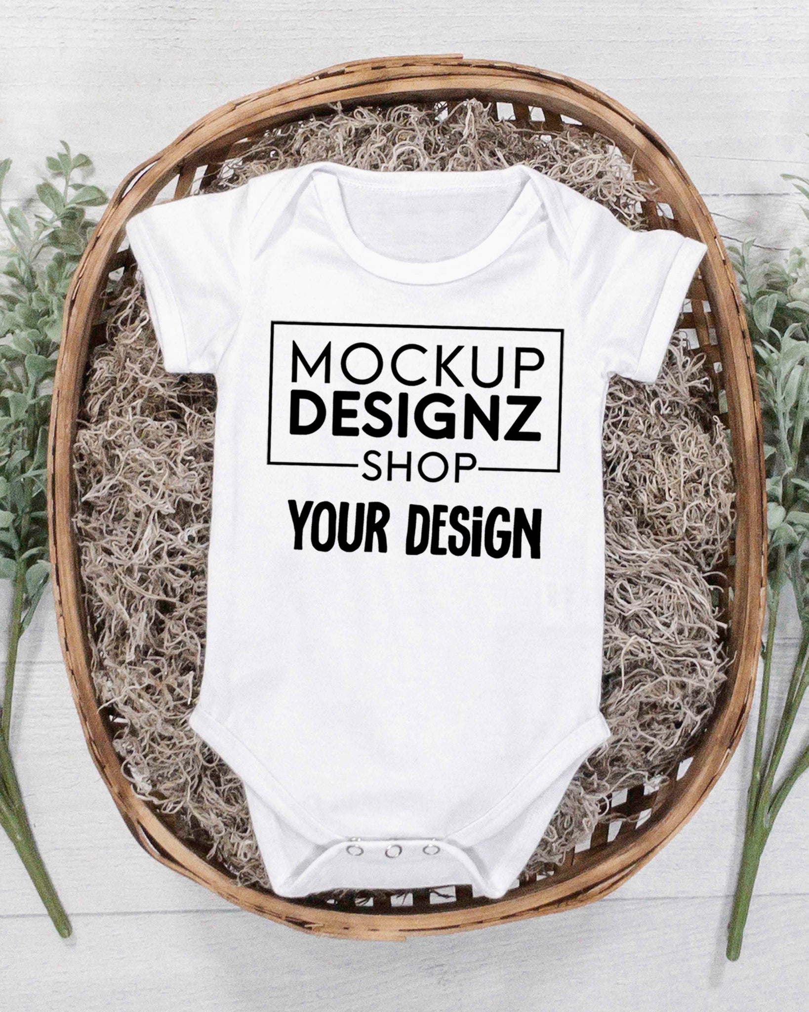 picture white onesie laid flat in a wicker basket with green plants portrait orientation